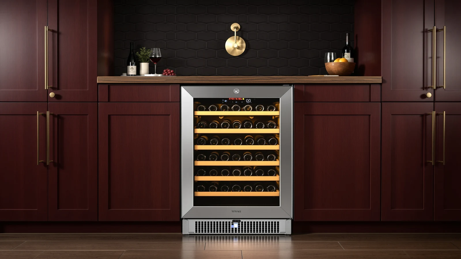 A stainless-steel and glass 15-inch undercounter wine refrigerator built into a kitchen cabinet run, bottles visible through the door